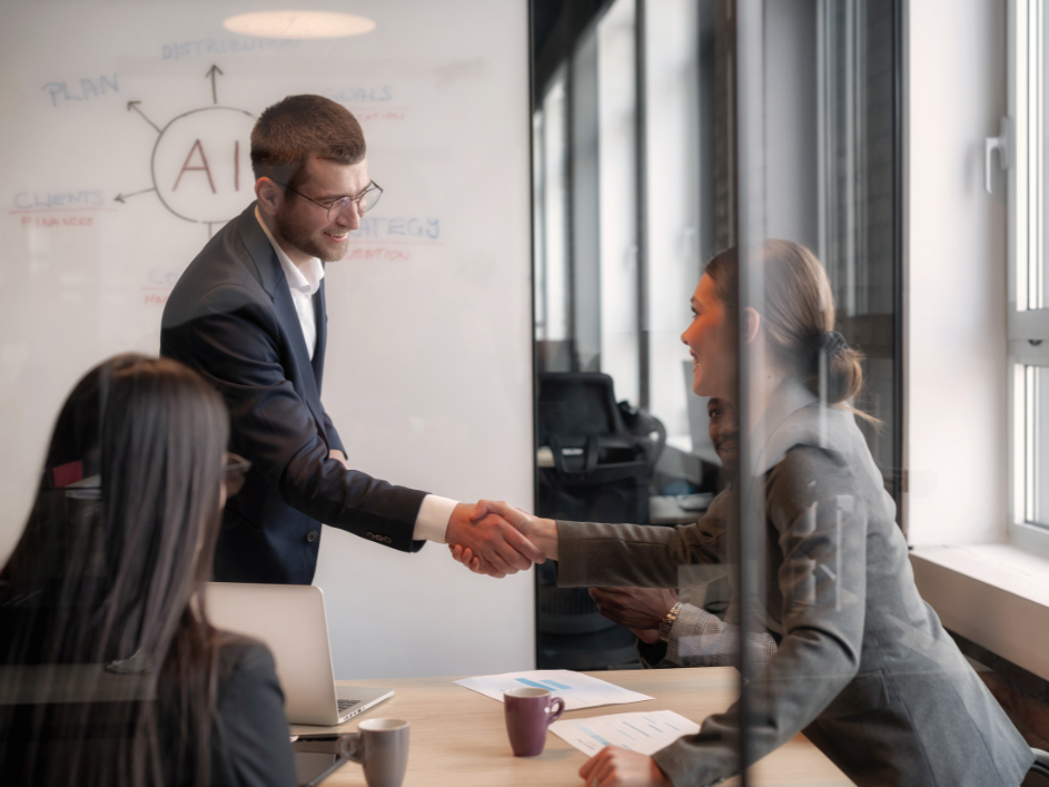 Two smiling professionals shaking hands in a AI strategy meeting.