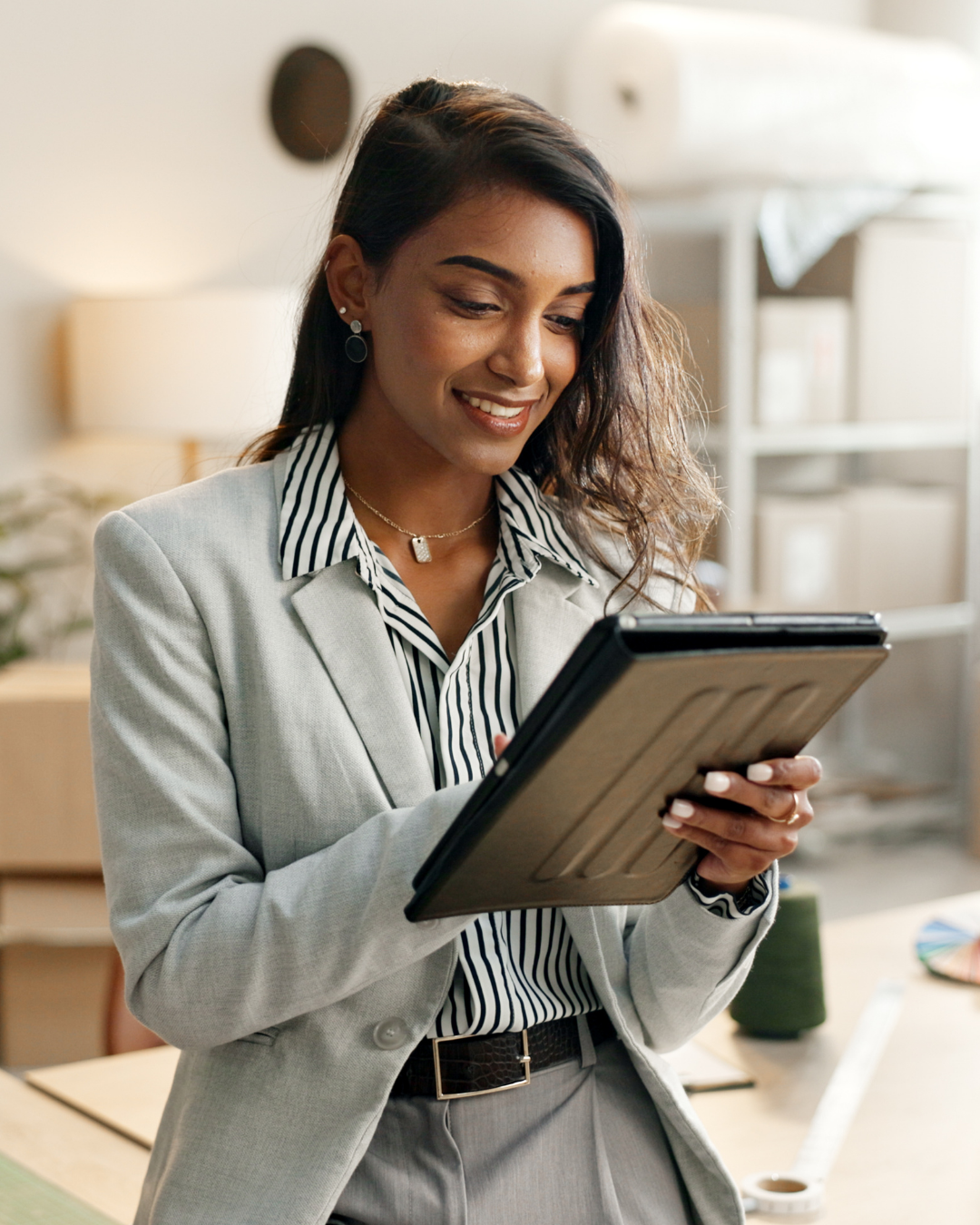 Woman in business clothes smiling while working on a tablet
